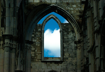 Fototapeta na wymiar Ruins of a castle, from the broken window you can see a beautiful sky with clouds