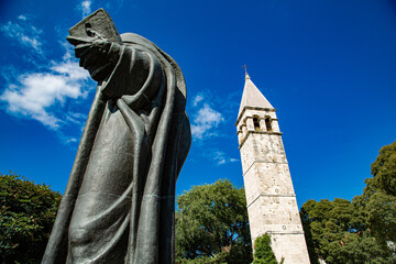 Torre campanario y gran estatua de bronce en parque con cielo de azul