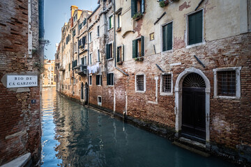 Fototapeta na wymiar Streets of Venice with a typical waterl canal during a sunny day, Italy