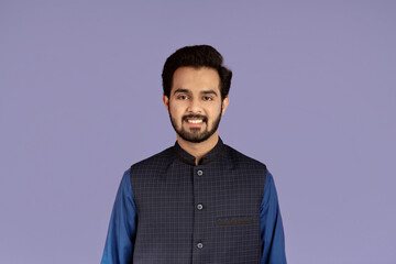 Handsome millennial man of Indian origin smiling on lilac background