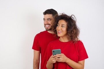 Copyspace photo of  Young beautiful couple wearing red t-shirt on white background stupor with something occurring in social media