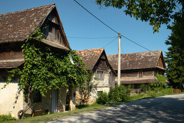 Fototapeta na wymiar The typical wooden house, green grass, bales of hay in the historical village Krapje in Lonsko polje reserve of Croatia