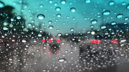 Rain falling on car windshield,colorful bokeh with street light,drive car on the road in city at...