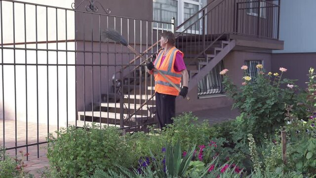 A cleaning lady on the street removes garbage. Cleanliness and order in the yard depends on the janitor during quarantine.