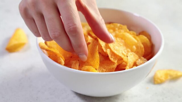 Eating potato chips with hands in a white bowl. Fast food concept.