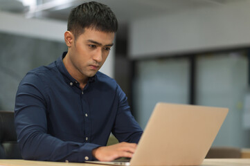 Young asian businessman working with laptop in office.