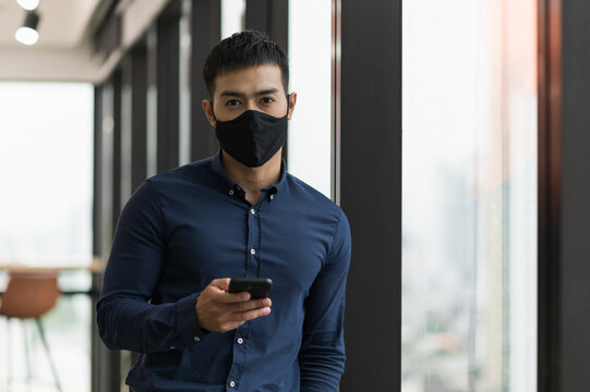 Business Asian Man Wearing Protection Face Mask Holding Smartphone Work In Office.