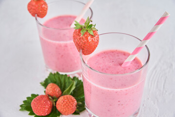 Strawberry milk shake in glass with straw and fresh berries on a white background