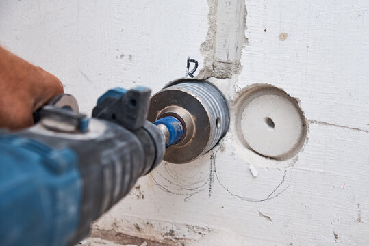 Builder with hummer drill perforator drills hole in a wall