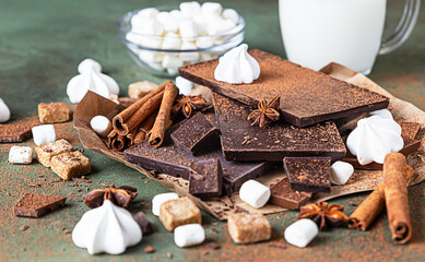 Ingredients for making hot chocolate. Dark and milk chocolate, cocoa powder, cinnamon, anise star, brown sugar, marshmallow, meringue and milk.