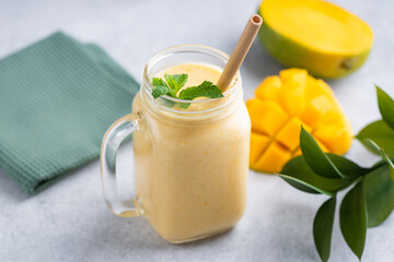 Tasty vegetarian mango smoothie in a glass with bamboo drinking straw