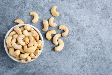 Cashews in bowl on concrete background, top view copy space