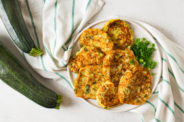 Zucchini pancakes with onion and parsley on white background