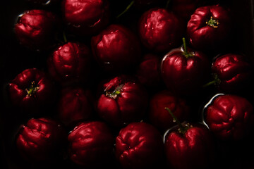 Porção de acerolas maduras dentro de vasilha cheia de água.