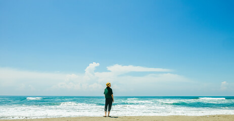 single girl enjoys herself standing on  Parangtritis beach, Yogyakarta, Indonesia.