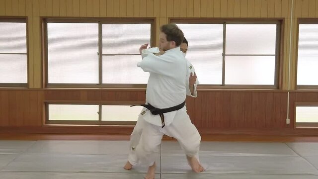 A Slow Motion Shot of a Judo Black Belt being thrown with a One Arm Shoulder Throw (Ippon Seoi Nage) in a traditional Japanese Dojo.