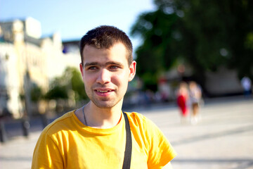 Happy, surprised Young man, student, tourist, dressed in a yellow t-shirt, looking away, against the backdrop of the city landscape. Happy young people. Concept of youth