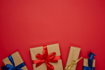 box wrapped in brown paper and tied with a blue silk ribbon with a bow, gift on a red background