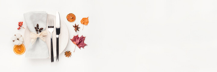 Thanksgiving autumn background. Plate with Cutlery and napkin decorated with autumn leaves, berries and spices. Top view.