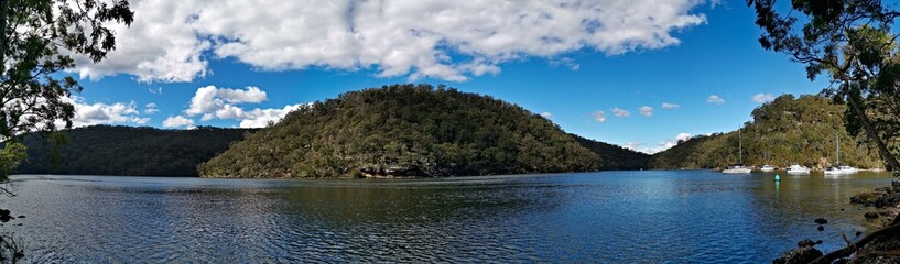Beautiful morning panoramic view of a creek with reflections of blue sky, boats, mountains and trees, Apple Tree Creek, Bobbin Head, Ku-ring-gai Chase National Park, New South Wales, Australia
