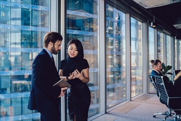 Successful woman formally dressed showing video about financial job during communication with male partner, diverse colleagues connecting to office wifi on modern technology reading trade news