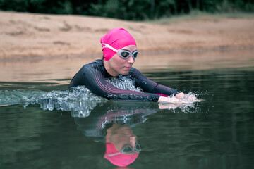 A female athlete swimmer dives into the water. Sports swimming, triathlon
