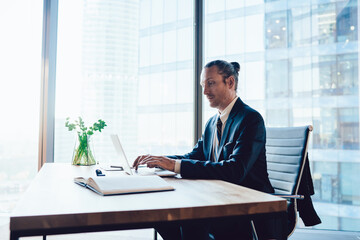 Determined businessman typing on laptop in contemporary workplace