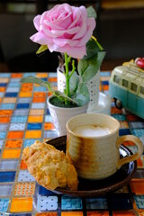 Hot coffee served with cookies on a brown mug and saucer.