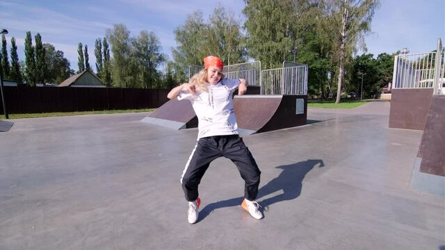 beautiful young woman in red bandana dancing hip hop choreography and break dance on a skateboard area
