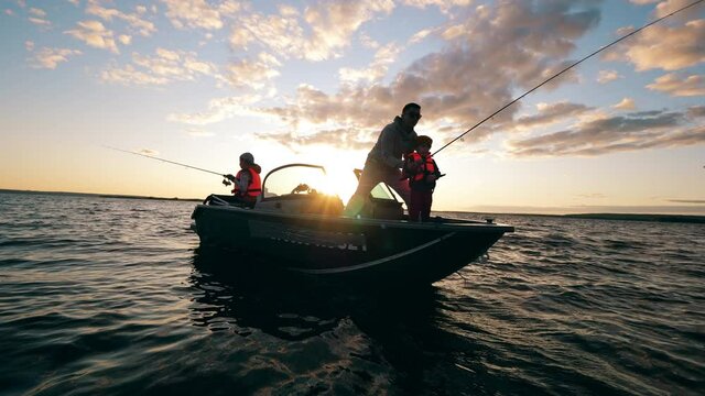 A father is helping his kids with fishing from a boat