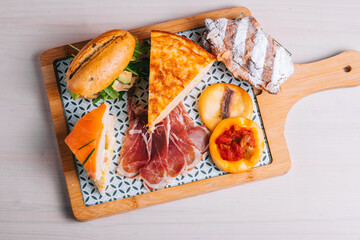 set of spanish breakfast for delivery omelette with potatoes Iberian ham sandwich on a wooden board