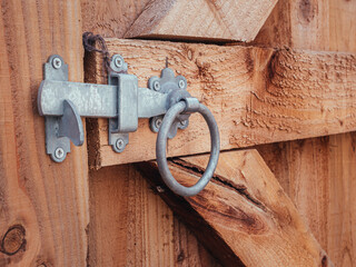 A Silver Bolt locked across a brown wooden gated and fence