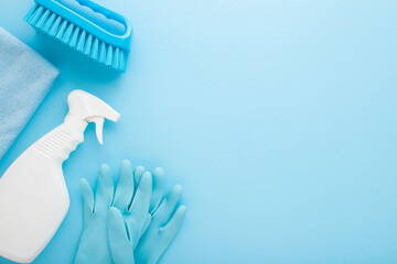 White bottle, rag, rubber protective gloves and brush. Cleaning set for different surfaces in kitchen, bathroom and other rooms. Light blue background. Top down view. Empty place for text or logo.