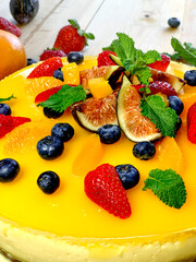 Delicious orange cheesecake decorated with fruits and mint leaves