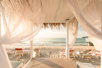 Fototapeta na wymiar canopy bed with white drapes on an empty beach