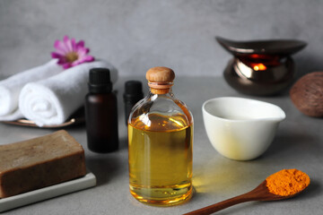 natural extract massage oil bottle is prepared for day spa massage on the grey stone table with cotton spa towel cloths, herbal soap , candle, curcuma powder and essential oil in the luxury Thai spa 