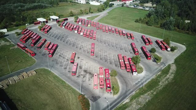 Red bus arriving in bus depot and parking aerial dynamic shot