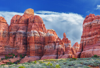 Rounded red rocks on a grassy mountain plateau under a cloudy sky.