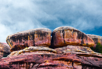 Rounded red rocks under a cloudy sky.