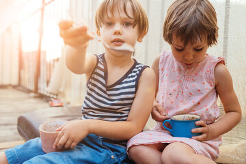 Group portrait of two white Caucasian cute adorable funny children toddlers sitting together sharing sweet food, love friendship childhood concept, best friends forever.