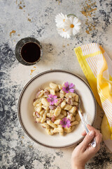 A plate full of butter gnocchi with malva flowers.