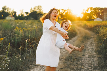 Obraz premium Woman playing with her child on the field during sunset.