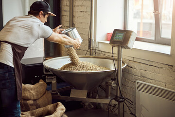 Male worker weighing coffee beans at factory