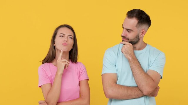 Young pensive couple friends bearded man woman in basic t-shirts posing isolated on yellow background studio. People emotions lifestyle concept. Thinking pointing index finger up with great new idea