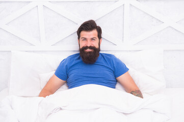 Laughing bearded man relax laying on bed at home, morning