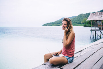 Young beautiful woman calling on pier near ocean