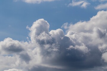 A portrait of a cloudy sky with a bit of blue sky at the top. The color of the clouds ranges from dark grey to white.