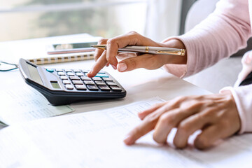 Young Asian woman record of income and expense at her desk. Home saving concept. Financial and...