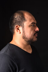 side view portrait of a latin american man on black  background