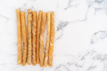 Rawhide dog chews against a white marble background.